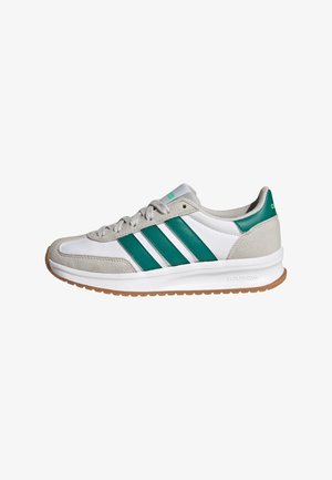 Sneaker bianca e grigia con strisce verdi Adidas e linguetta sul tallone, lacci grigi, suola intermedia bianca e suola esterna color gomma su sfondo bianco.