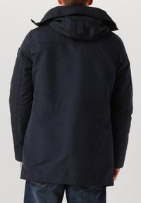 Marineblauwe waterdichte jas met een capuchon, voorzien van een rechte snit en zijzakken, gemaakt van duurzaam materiaal met een gladde textuur.