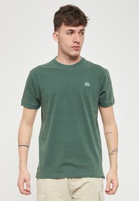 T-shirt verde in cotone con maniche corte, scollatura rotonda e un piccolo logo ricamato sul lato sinistro del petto. Tessuto morbido, vestibilità casual.