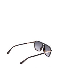 Lunettes de soleil avec monture écaille, verres à dégradé foncé et fines branches en métal rose doré reposant sur une surface blanche.