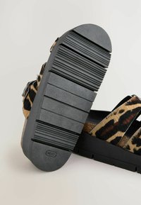 Leopardprint instapsandalen met zwarte rubberen zolen. Brede banden met een harige textuur en een verstelbare gesp, met een platte en geprofileerde zool.