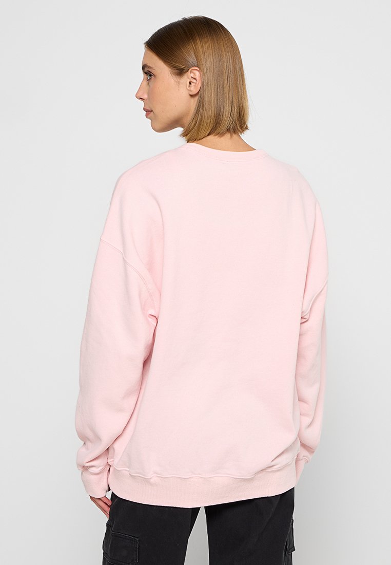 Helles rosa Oversized-Sweatshirt aus weichem Stoff, mit Rundhalsausschnitt und gerippten Bündchen, lockerem Schnitt und minimaler Gestaltung.