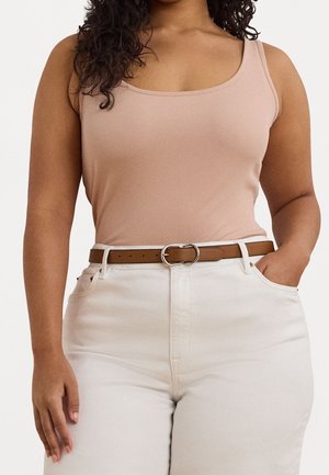 Débardeur côtelé rose clair associé à un pantalon blanc taille haute et une ceinture marron avec une boucle en métal. Bretelles courtes et coupe ajustée.