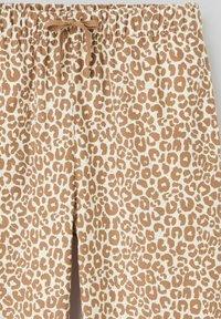 Pantalons imprimés léopard dans des tons beiges et bruns, avec une taille élastique à cordon, en tissu coton et une coupe décontractée.