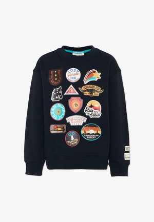 Felpa blu navy con toppe colorate che rappresentano temi del Texas come Longhorn BBQ, deserto di Chihuahuan, cavalli, tramonti e slogan giocosi.