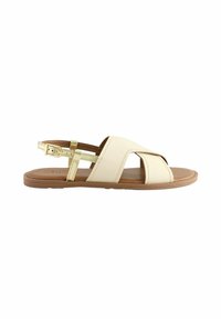 Sandali incrociati beige realizzati in morbida pelle con un accento dorato e una suola imbottita, dotati di una cinghia alla caviglia regolabile per una vestibilità perfetta.