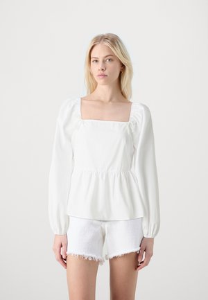 Valkoinen pitkähihainen paita, jossa on neliömäinen kaula-aukko ja röyhelödetaljeja. Sisältää kanavia solmimisnauhoille, jotka on koristeltu helmillä. Peplum-tyyli.