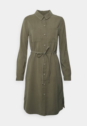 Abito camicia verde oliva con collo a camicia, maniche lunghe, due tasche sul petto, chiusura frontale con bottoni e cintura annodata in vita. Tessuto liscio.