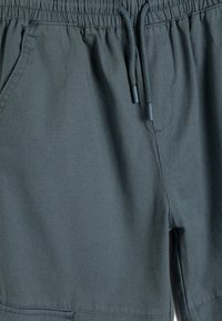 Pantalones cortos de color verde oscuro con una cinturilla elástica y cordón ajustable, que cuentan con bolsillos laterales y una textura de tela suave.