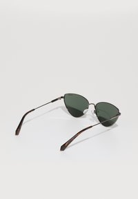Cat-eye sunglasses with green lenses, tortoiseshell tips, and metal frames. Features nose pads and a slender design.