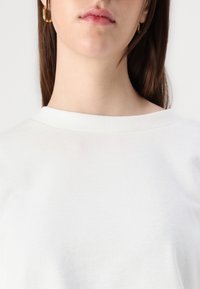 Sudadera de algodón blanca con un cuello redondo acanalado, textura suave y sin patrones ni adornos visibles.
