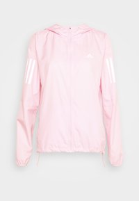 Jasnoróżowa kurtka Adidas wykonana z gładkiego materiału, z zamkiem błyskawicznym z przodu, kapturem oraz trzema białymi paskami na każdym rękawie.