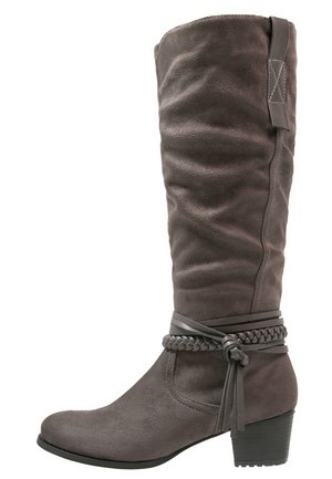 Botte haute en daim gris foncé avec un petit talon bloc, des brides tressées et lisses attachées autour de la cheville, et une languette de tirage en haut.