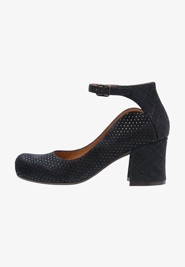 Chaussure noire texturée à petit talon bloc avec bride de cheville et boucle, bout arrondi et petit motif de points perforés sur le dessus.
