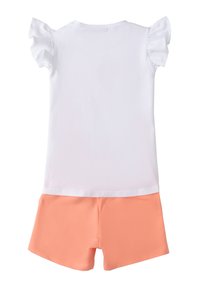 Top blanco de manga corta con acentos de volantes, combinado con pantalones cortos de color coral. El material parece suave con una textura lisa.