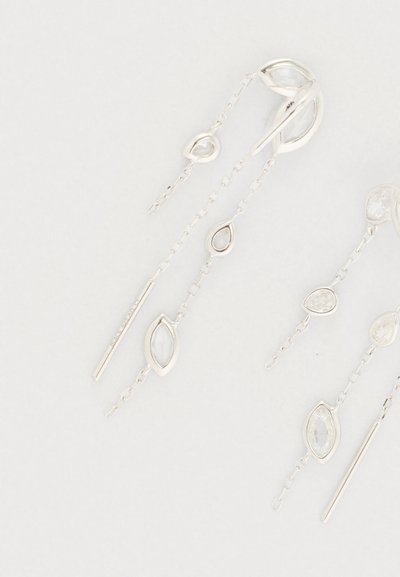 Brincos de pendente prateados com várias correntes, apresentando pedras preciosas claras de diferentes formatos e um elegante detalhe em barra. Design sofisticado.