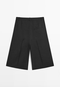 Short large noir longueur genou avec passants de ceinture et une poche passepoilée arrière unique côté droit, présenté à plat sur fond blanc.