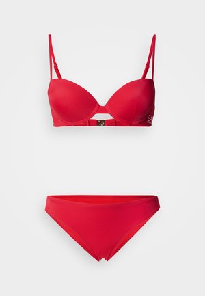 Σετ κόκκινου μπικίνι με επενδυμένο σουτιέν που διαθέτει ρυθμιζόμενες τιράντες και κεντρικό κούμπωμα, συνοδευόμενο από ταυτόχρονες σλιπ με ψηλό κόψιμο. Ομαλή υφή.