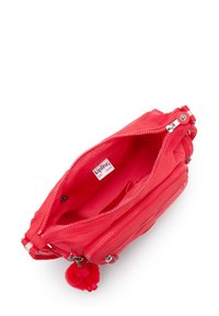 Roter Reißverschlusstasche aus Nylon, mit mehreren Fächern, einem plüschigen Pom-Pom-Schlüsselanhänger und einem Logoschild im Inneren.