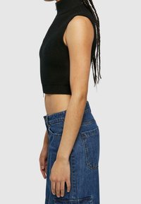 Svart randig ärmlös crop top med hög krage, kombinerad med högmidjad blå denimkjol med fickor och synlig sömnad.