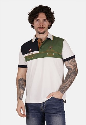 Polo con una combinazione di pannelli blu navy, verde oliva e bianco. Presenta una chiusura con tre bottoni, dettagli ricamati e un tessuto di cotone texturizzato.