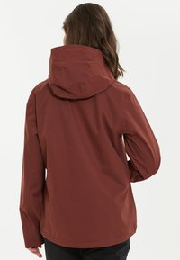Vattentålig röd jacka med huva, långa ärmar och rak skärning. Slät textur och minimalt design, lämplig för utomhusbruk.
