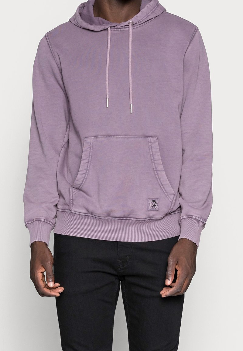 Lila hoodie med en framficka, dragskohuva, ribbade ärmslut och fåll. Har en logotypetikett på fickan. Mjuk tygtextur.