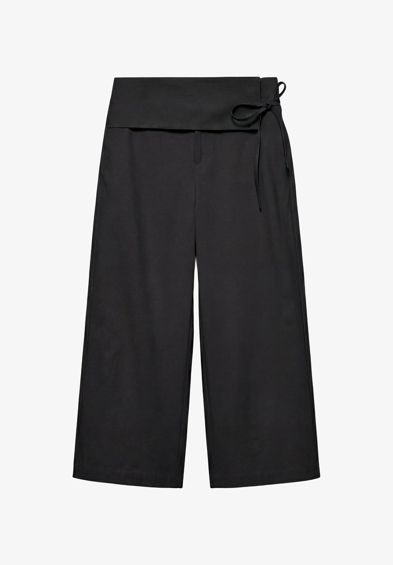 Pantalon noir à jambes larges avec une taille haute repliée et une fine ceinture nouée sur le côté droit.