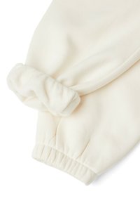 Biała, miękka tkanina rękawa z marszczonym mankietem i złożonym, puszystym akcentem. Faktura wydaje się gładka i przytulna z delikatnym opadaniem.