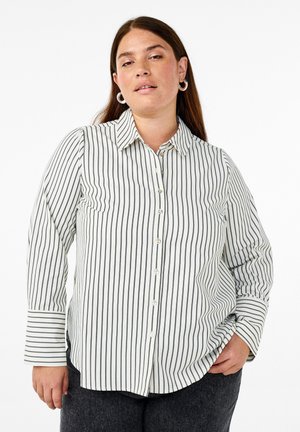 Hvid skjorte med knaplukning og smalle sorte lodrette striber, klassisk krave, lange ærmer og en buet forneden. Har subtile lomme detaljer.
