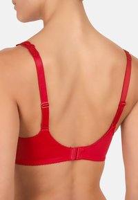 Czerwona braletka z koronkowymi akcentami, regulowanymi ramiączkami i zapięciem na haczyk. Wykonana z gładkiego materiału z falistym wykończeniem wzdłuż krawędzi.