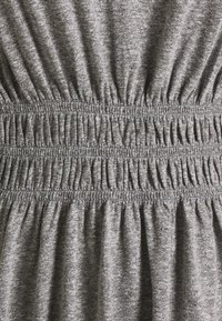 Szary dzianinowy materiał z marszczoną elastyczną talią, charakteryzujący się fakturowanym wyglądem i subtelnym melanżowym wzorem na powierzchni.