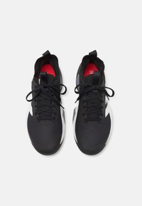 Baskets de sport noires avec une tige en mesh, un laçage ton sur ton, des accents blancs contrastants et une doublure intérieure rouge. Semelle extérieure en caoutchouc lisse pour une meilleure traction.