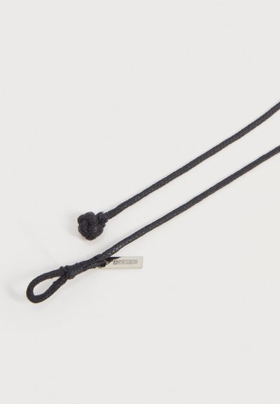 Cordon tressé noir avec une boucle à une extrémité, un nœud à l'autre, et une petite étiquette en argent gravée de "MOSCHINO" près de la boucle.