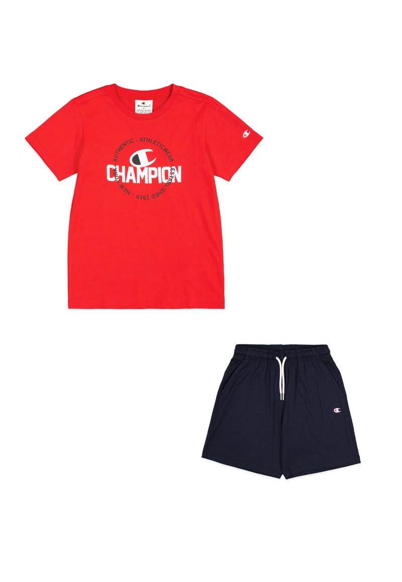 Camiseta de algodón roja con el logo "CHAMPION" en blanco, combinada con pantalones cortos azul marino que tienen una cintura elástica y bolsillos laterales.