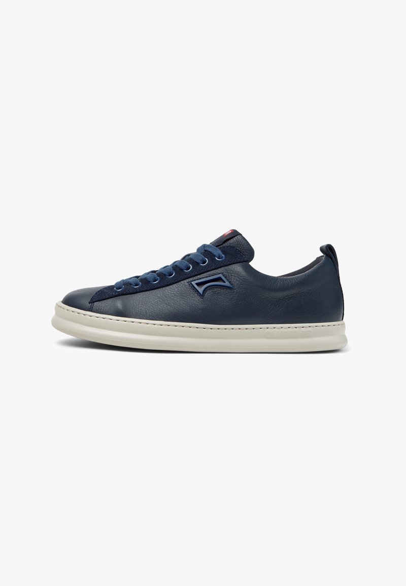 Marineblauwe leren sneaker met ronde neus, contrasterende witte rubberen zool, blauwe veters en een klein logodetail aan de zijkant. Minimalistische stiksels als accent.