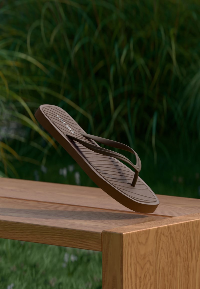 Καφέ σαγιονάρα ισορροπημένη στην άκρη ξύλινου τραπεζιού σε υπαίθριο χώρο με ψηλό πράσινο γρασίδι στο φόντο.