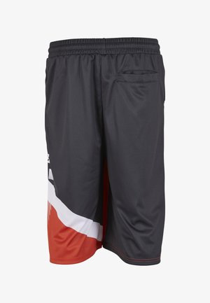 Mustad sportpüksid elastse vöökohaga, tagatasku ja punaste ning valgete geomeetriliste aktsentidega alumisel vasakul jalal.