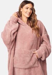 Felpa in pile rosa oversize con una grande tasca frontale, un cappuccio ampio e tessuto texturizzato. Caratterizzata da maniche larghe e una vestibilità confortevole.