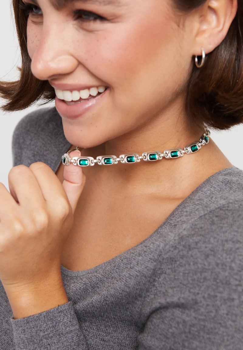 Gargantilla de plata con piedras rectangulares verde azulado, con un diseño enlazado y textura suave, llevada alrededor del cuello.