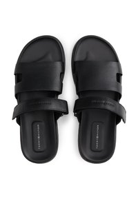 Μαύρα σανδάλια με ανοιχτό σχέδιο, κατασκευασμένα από λείο συνθετικό υλικό με δύο φαρδιές, επίπεδες λουρίδες. Διακριτικό λογότυπο στη σόλα.