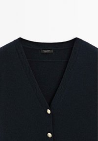 Cardigan noir à col en V avec bords côtelés et deux boutons dorés visibles près du centre devant, étiquette à l’intérieur indiquant Massimo Dutti.