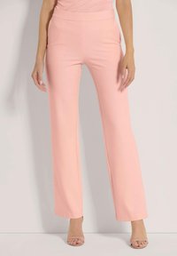 Lichtroze uitlopende broeken van een soepel, rekbaar materiaal met een brede tailleband. De broek heeft een strakke uitstraling zonder versieringen.