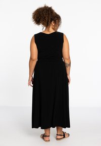 Zwarte, mouwloze maxi-jurk met een relaxte pasvorm, met een ronde halslijn en een iets verzamelde taille, weergegeven vanaf de achterkant.