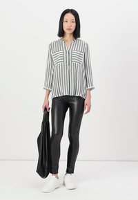 Rutet grå og hvit skjorte med henleykrage over sorte blanke leggings; paret med hvite sneakers og en svart totebag.