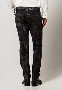 Jeans in denim nero con un motivo bianco screpolato, vestibilità slim e design a cinque tasche. Finiti con hardware in metallo e dettagli di cucitura sottili.