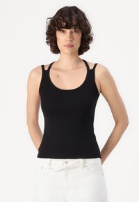 Black tank top with a scoop neck, featuring thin straps and a fitted design. Made from smooth, stretchy fabric.