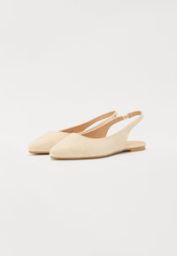 Ballerines à talons ouverts en tissu beige avec un bout pointu, une semelle plate et une texture lisse. Design simple avec un détail découpé au niveau du talon.