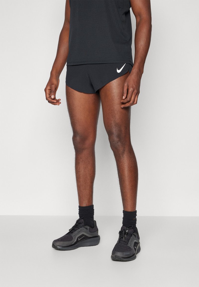 Svarte joggeshorts med en hvit Nike-logo, kombinert med svarte sneakers og sokker, som viser et enkelt og funksjonelt design.
