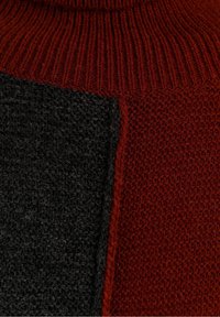 Strickpullover mit hohem Kragen, kontrastierenden dunkelgrauen und tiefroten Paneelen sowie einem strukturierten Strickmuster.